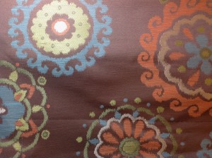 Upholstery fabric with brown background and large flower patterns. 